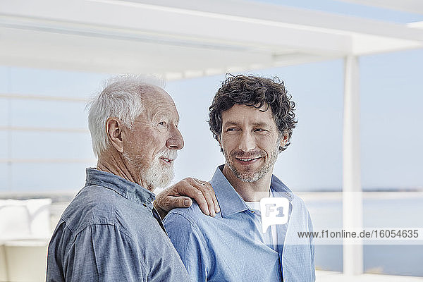 Porträt eines älteren Mannes mit erwachsenem Sohn in einem Strandhaus