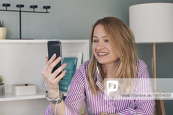Nahaufnahme einer lächelnden Geschäftsfrau bei einem Videoanruf über ein Smartphone im Büro