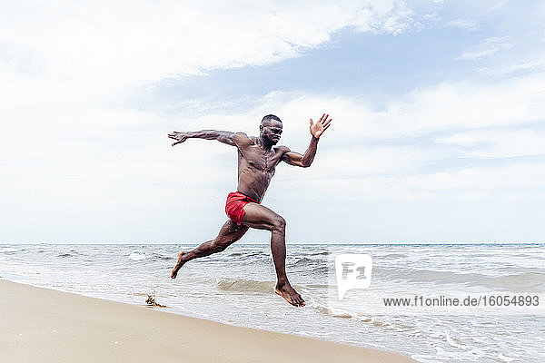 Sportlicher Mann läuft am Strand