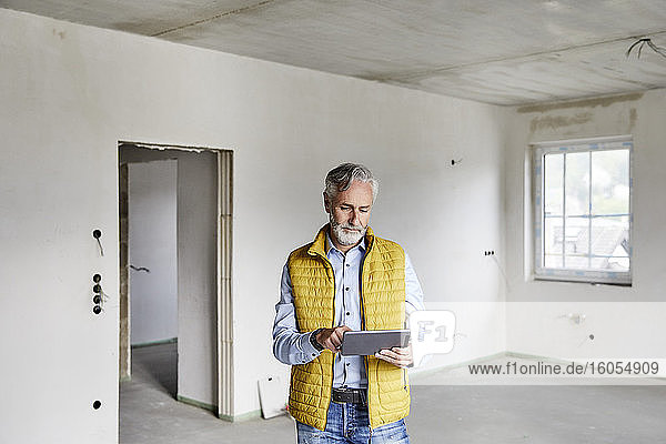 Älterer Mann benutzt Tablet auf einer Baustelle