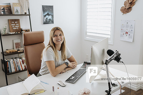 Lächelnde Geschäftsfrau  die zu Hause einen Computer auf dem Schreibtisch benutzt