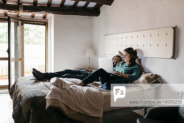 Couple watching movie sitting on bed at home