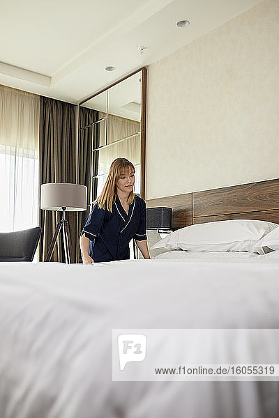 Zimmermädchen macht Bett im Hotelzimmer