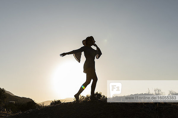 Junge Frau steht auf einem Hügel auf dem Lande gegen den klaren Himmel