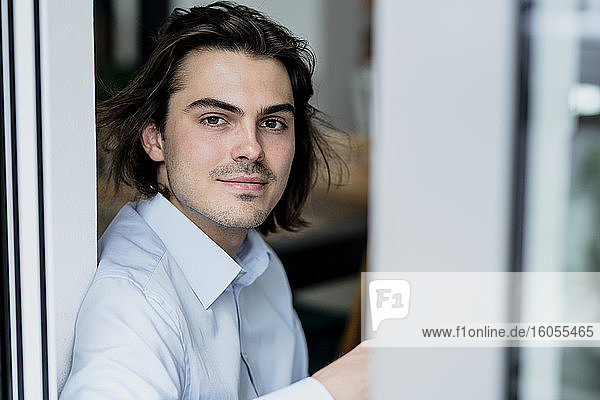 Close-up of handsome businessman looking through window while sitting in cafe