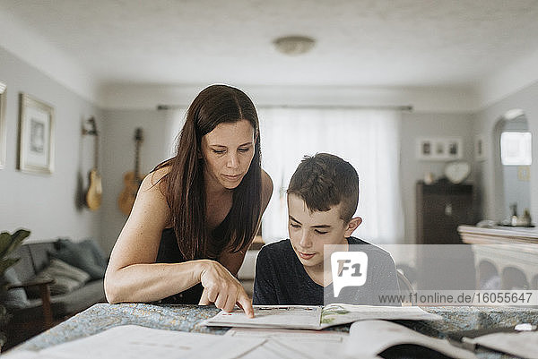 Mutter unterrichtet Sohn während der Ausgangssperre zu Hause auf dem Tisch