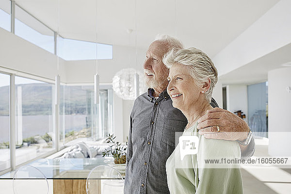 Glückliches älteres Paar in luxuriösem Strandhaus mit Blick aus dem Fenster