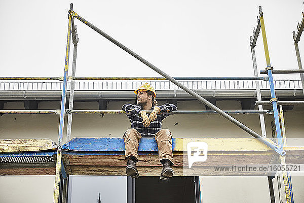 Arbeiter macht eine Pause auf einem Baugerüst auf einer Baustelle