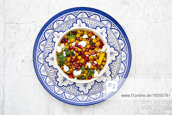 Schüssel mit vegetarischem Salat mit Kichererbsen  Kurkuma  Paprika  Tomaten  Petersilie  Feta-Käse und Granatapfelkernen