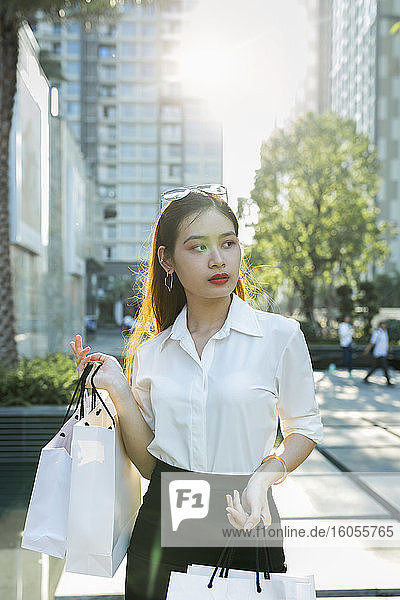 Selbstbewusste junge Frau mit Einkaufstüten in der Hand in der Stadt stehend