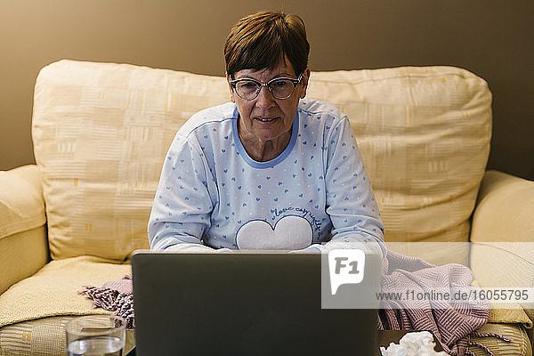 Eine ältere Frau im Ruhestand bespricht ihre Krankheit mit einem Arzt per Videoanruf über ihren Laptop zu Hause
