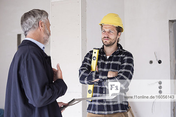 Architekt und Bauarbeiter diskutieren im Stehen über den Bau eines Hauses