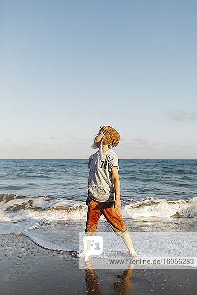 Boy wearing aviator's cap while standing at beach