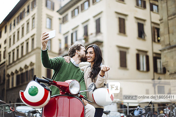 Romantic man taking selfie while kissing woman in Florence city  Italy