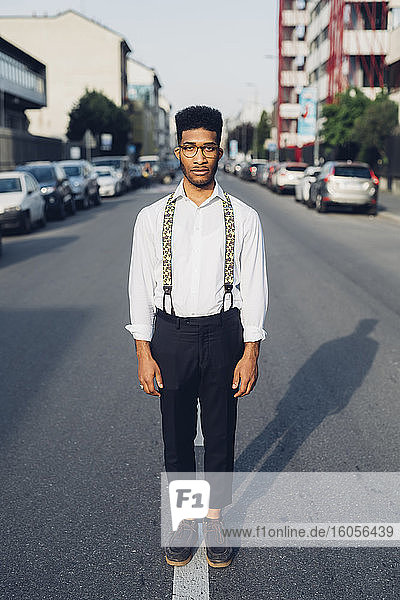 Portrait of a confident stylish young man standing on the street in the city