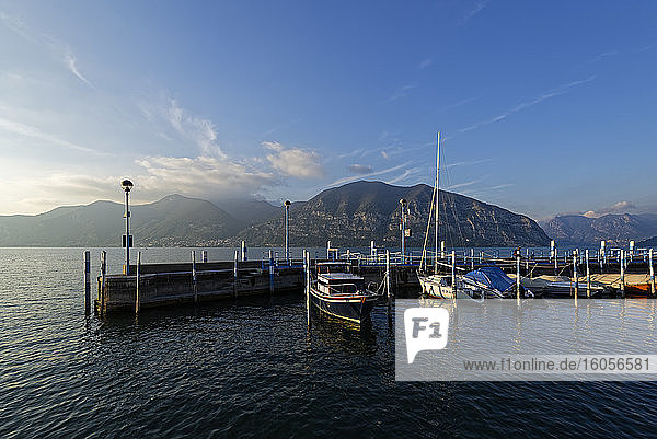 Italy  Lombardy  Boats moored at pier on lake Iseo at sunset