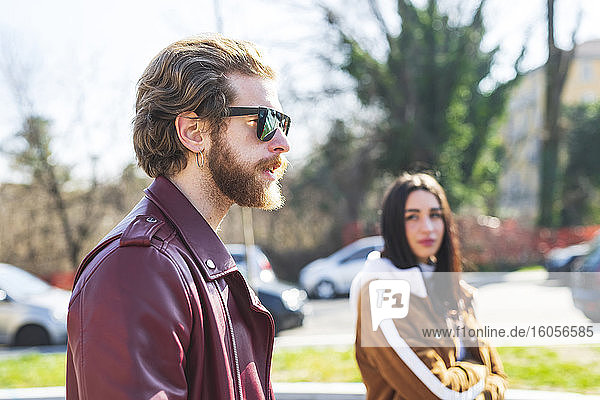 Nahaufnahme eines Mannes mit Sonnenbrille  der mit seiner Freundin in der Stadt spazieren geht
