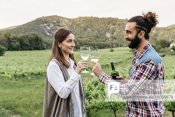 Glückliches Paar stößt mit Weingläsern im Weinberg an