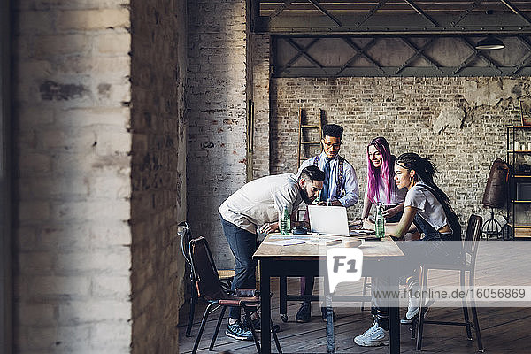 Creative team having business meeting in loft office using laptop