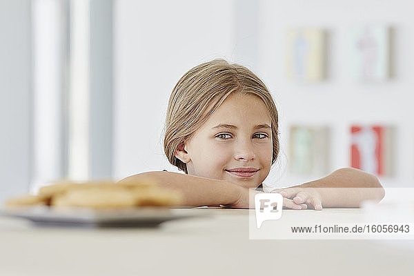 Porträt eines niedlichen Mädchens zu Hause mit Teller auf dem Tisch