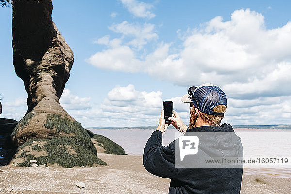 Mann fotografiert eine Felsformation im Hopewell Rocks Park  New Brunswick  Kanada