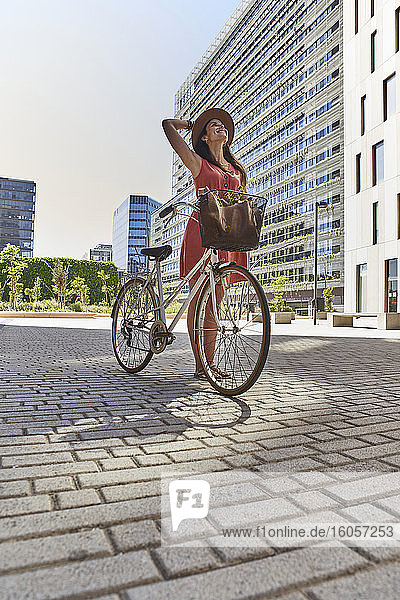Nachdenkliche Frau steht mit Fahrrad auf der Straße