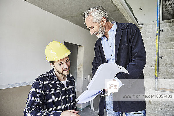Architekt und Arbeiter besprechen einen Bauplan auf einer Baustelle