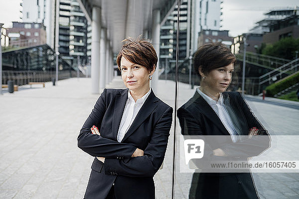 Businesswoman with arms crossed standing by modern building in city