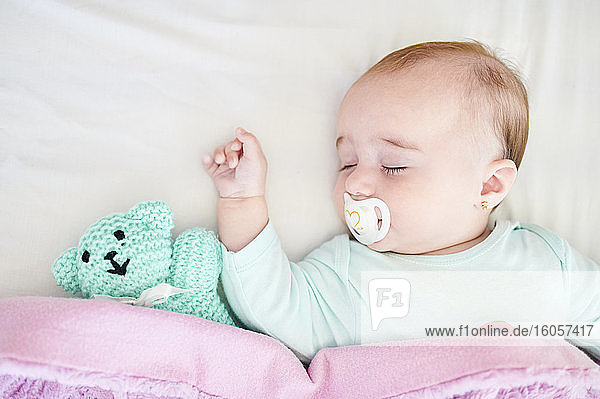 Porträt eines schlafenden kleinen Mädchens mit Schnuller und Kuscheltier