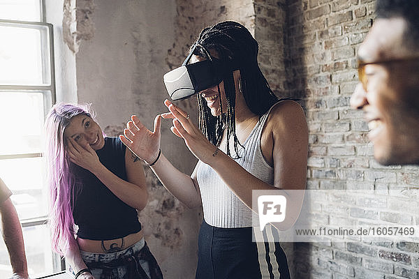 Happy creative team using Vr goggles in loft office