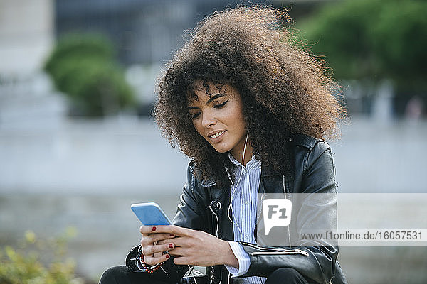 Junge afroamerikanische Frau surft im Internet auf einem Smartphone