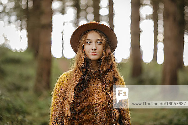 Beautiful woman with long hair wearing hat standing in forest