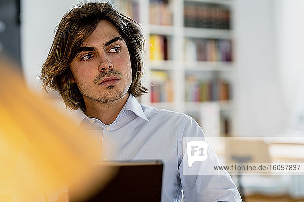 Close-up of thoughtful male professional with digital tablet sitting in coffee shop