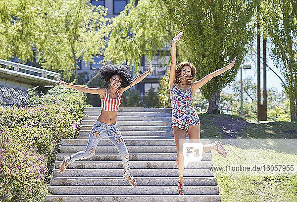 Girlfriends jumping from stairs in park