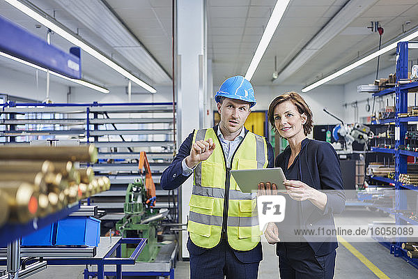 Vorgesetzter und Managerin diskutieren über ein digitales Tablet in einer Fabrik