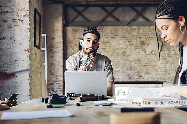 Portrait of creative business man sitting at table in loft office