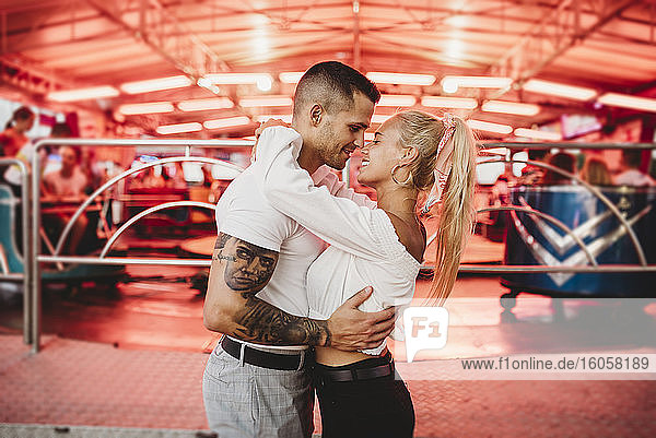 Romantisches junges Paar  das sich in einem Vergnügungspark umarmt