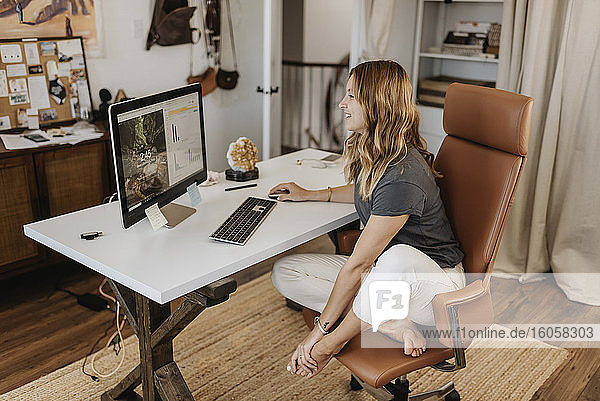 Frau mit Computer auf dem Schreibtisch zu Hause