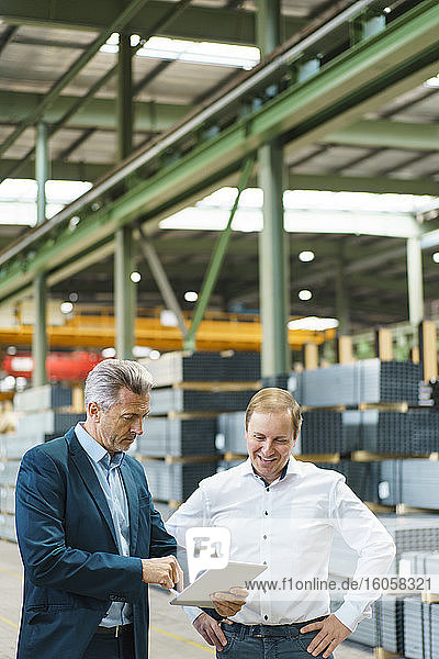 Zwei Geschäftsleute benutzen ein Tablet in einer Fabrik