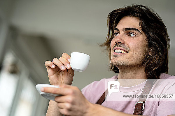 Close-up of smiling male owner holding coffee in cafe