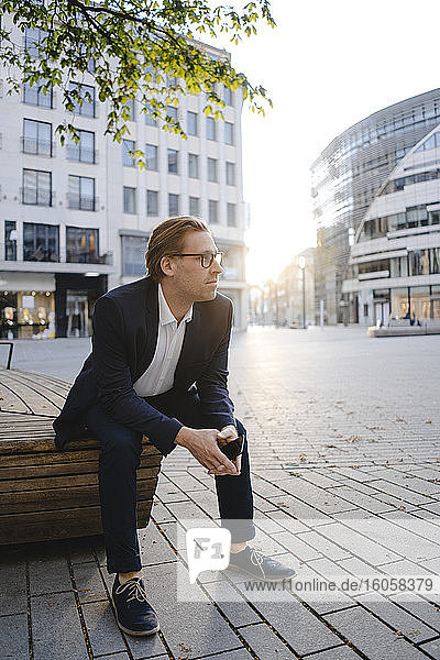 Businessman sitting on a bench in the city