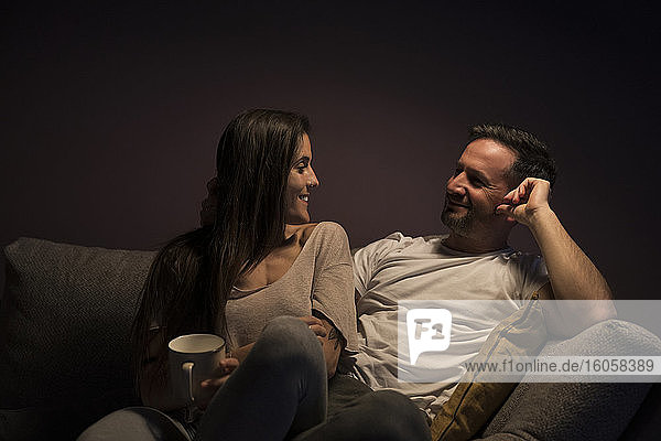Glückliches Paar  das sich gegenseitig ansieht  während es sich auf dem Sofa zu Hause entspannt