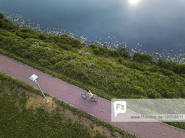 Russland  Tichwin  Luftaufnahme einer Radfahrerin auf einem Fußweg am Seeufer im Park