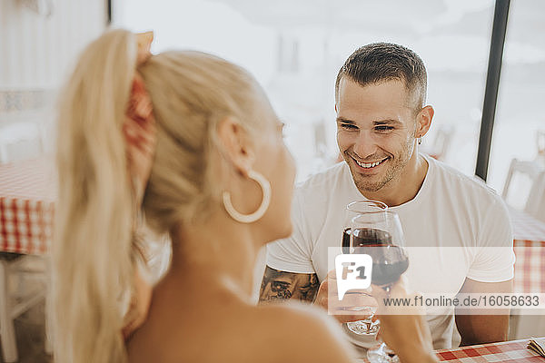 Happy young couple toasting wineglasses in restaurant