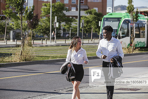 Geschäftsleute diskutieren beim Gehen auf dem Bürgersteig in der Stadt an einem sonnigen Tag