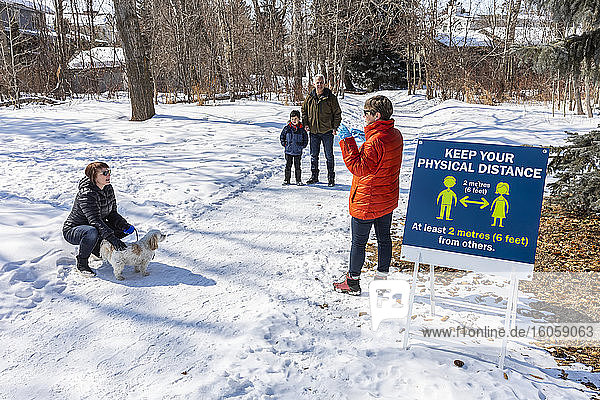 Families stand to visit at a distance on a path through a park during the Covid-19 world pandemic; St. Albert  Alberta  Canada