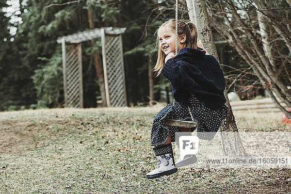 Portrait of a young girl swinging on a swing; Alberta  Canada