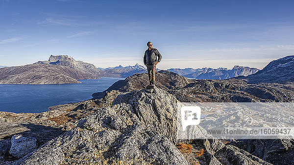 Ein Mann blickt aus der zerklüfteten Landschaft an der grönländischen Küste heraus; Sermersooq  Grönland