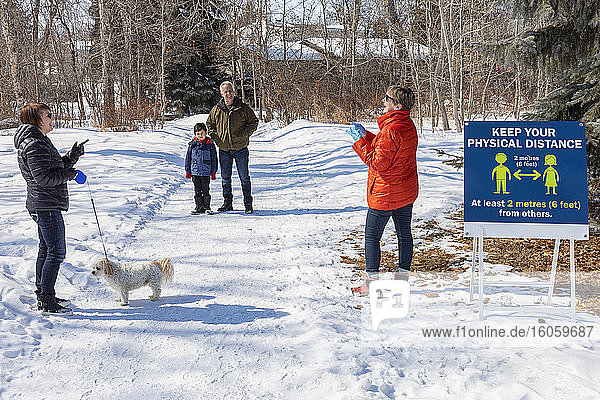 Families stand to visit at a distance on a path through a park during the Covid-19 world pandemic; St. Albert  Alberta  Canada