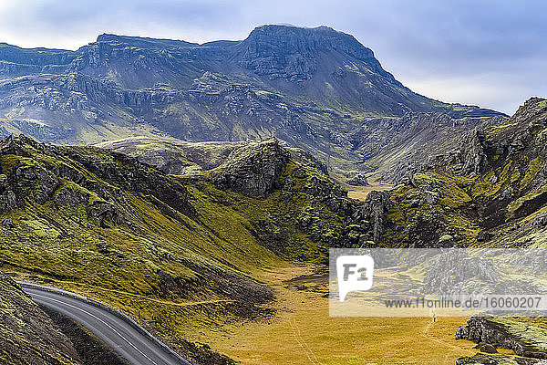 Eine Straße schlängelt sich durch eine zerklüftete Landschaft in Südisland; Grimsnes- og Grafningshreppur  Südliche Region  Island